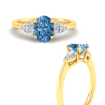 Load image into Gallery viewer, 3-stone-vivid-blue-oval-shaped-cathedral-ring-in-yellow-gold-fdenr9210ovgvblueangle3-nl-yg.jpg